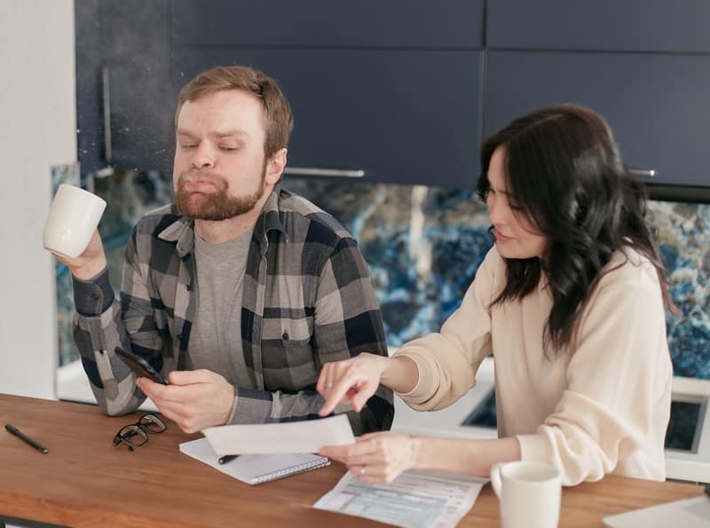A couple at their kitchen table, working through a stack of medical bills together