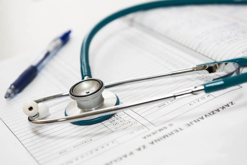 A stethoscope and pen resting on a printed medical report